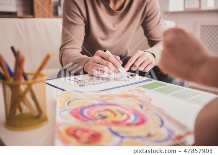 Colorful picture lying on table near pencils Colorful picture lying on table near pencils 47857903