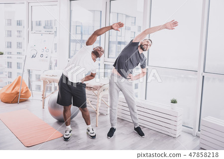 Positive delighted males doing training in gym Positive delighted males doing training in gym 47858218