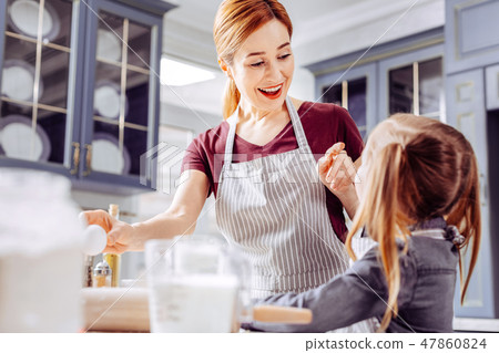 Happy woman smiling and pointing to the cookie of her little daughter 47860824