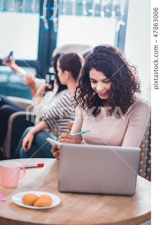 Delighted positive woman sitting in front of the laptop Delighted positive woman sitting in front of the laptop 47863006