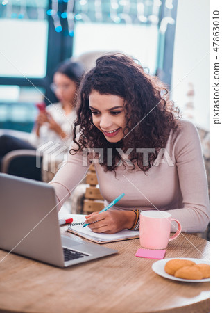 Positive nice woman taking notes in the notebook Positive nice woman taking notes in the notebook 47863010