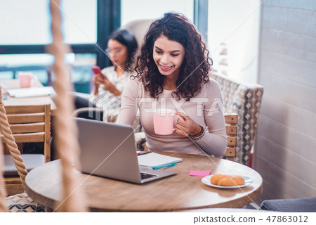 Joyful nice woman sitting in front of the laptop 47863012