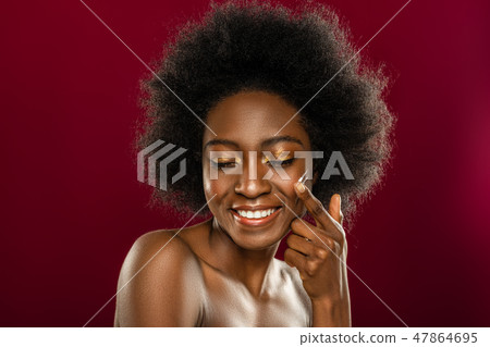 Face of a cheerful young woman while applying cream Face of a cheerful young woman while applying cream 47864695