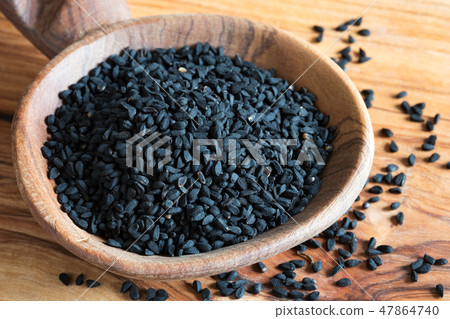 Black cumin seeds on a wooden spoon 47864740