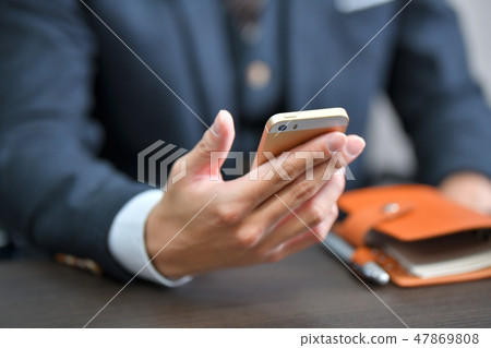 Hand of a business man with a smartphone (smartphone). Business scene. 47869808