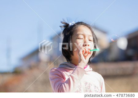 Girl playing soap bubbles Girl playing soap bubbles 47873680