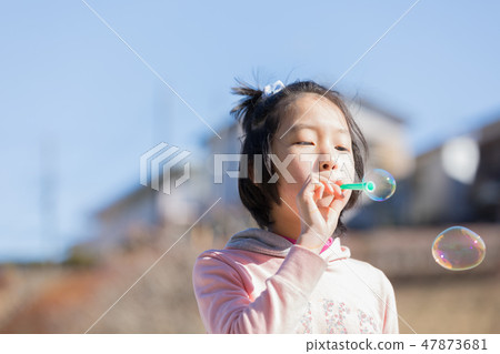 Girl playing soap bubbles Girl playing soap bubbles 47873681