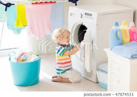 Child in laundry room with washing machine Child in laundry room with washing machine 47874531