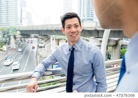Asian businessman talking with colleague outdoors Asian businessman talking with colleague outdoors 47876306