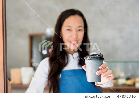 Asian female cafe staff giving takeaway coffee cup Asian female cafe staff giving takeaway coffee cup 47876310