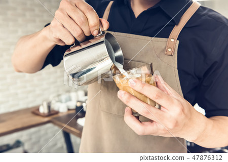 Barista pouring steamed milk into coffee cup Barista pouring steamed milk into coffee cup 47876312