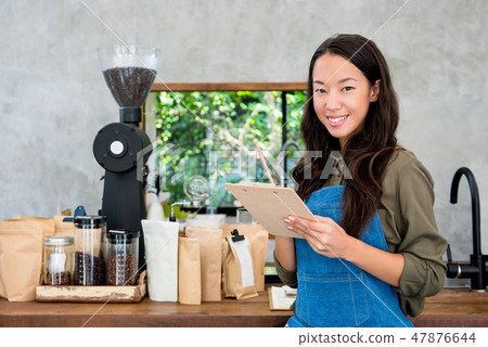 Smiling young Asian woman entrepreneur at her cafe Smiling young Asian woman entrepreneur at her cafe 47876644