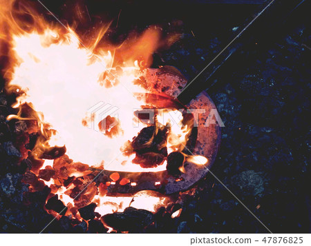 Forge with strong flames. Pliers hold horse shoe Forge with strong flames. Pliers hold horse shoe 47876825