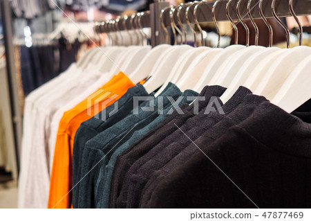 Stylish multicolored sweaters on rack 47877469