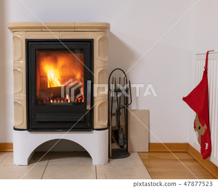 Tiled stove with fire burning inside 47877523