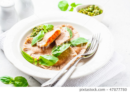Pumpkin ravioli with pesto sauce in a white plate. 47877780