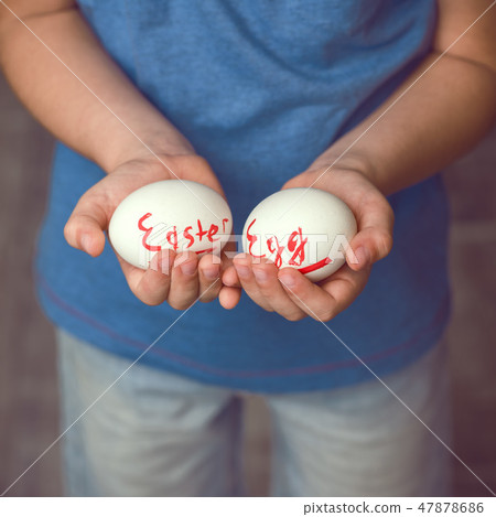 Eggs with the inscription Happy Easter the child holds in her hands in front of him. Eggs with the inscription Happy Easter the child holds in her hands in front of him. 47878686