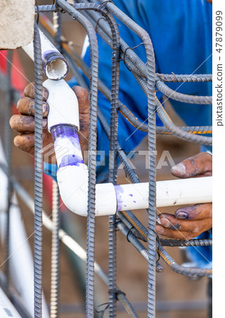 Plumber Installing PVC Pipe at Construction Site Plumber Installing PVC Pipe at Construction Site 47879099