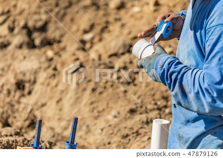 Plumber Applying PTFE Tape To PVC Pipe At Jobsite 47879126