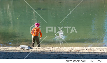 a child throws stones into the water 47882513