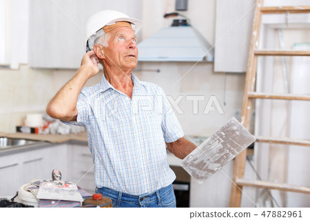 Foreman with plastering tools looking at repairable room 47882961