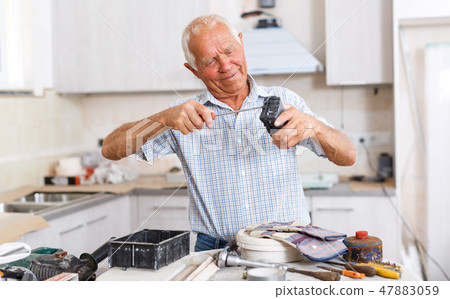 Senior man working on apartment overhauls Senior man working on apartment overhauls 47883059