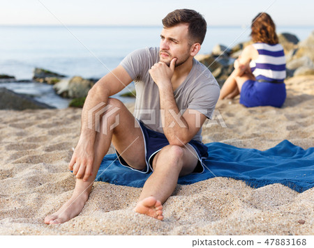 Man sitting with displeasure on the beach Man sitting with displeasure on the beach 47883168