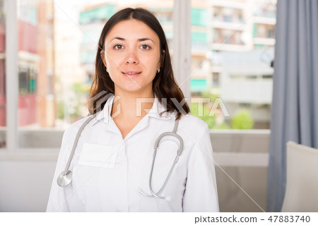 Young woman doctor in white uniform standing in clinic's office 47883740