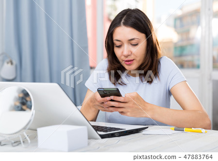 Young girl student using laptop and phone at the home 47883764