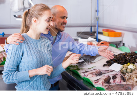 customers choosing seafood in fish store and smiling customers choosing seafood in fish store and smiling 47883892