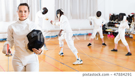 Portrait of smiling sporty young woman with foil at fencing workout Portrait of smiling sporty young woman with foil at fencing workout 47884291