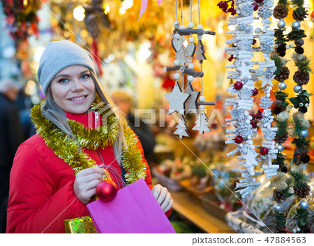 Positive female with handmade Christmas gifts on the street market Positive female with handmade Christmas gifts on the street market 47884563