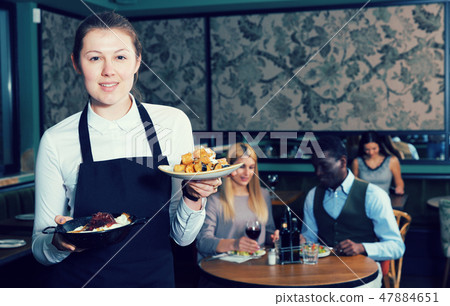 Smiling waitress with ordered dishes 47884651