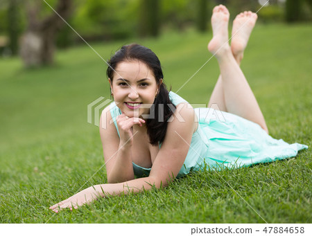 portrait of smiling young girl while lying in outdoors 47884658