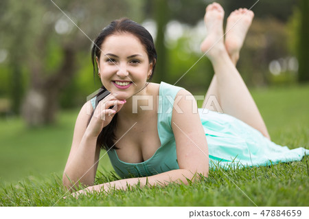 portrait of smiling young girl while lying in outdoors 47884659