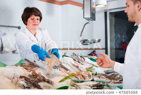 woman selling fish to male customer 47885088