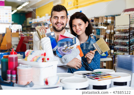 Couple purchasing tools for house improvements in paint supplies store 47885122