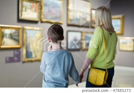 Mother and son regarding paintings in halls of museum 47885273