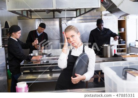 Unhappy waitress waiting dishes in kitchen Unhappy waitress waiting dishes in kitchen 47885331