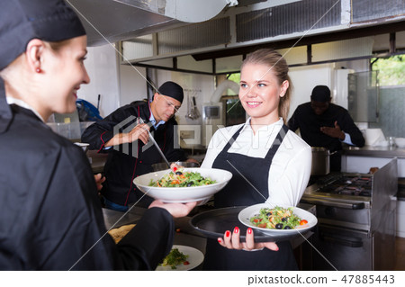 Waitress taking cooked meals from chef 47885443