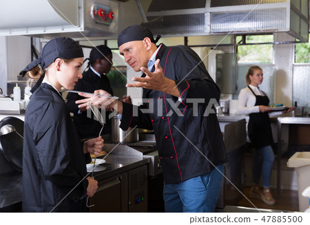 Exasperated chef scolding female employee Exasperated chef scolding female employee 47885500
