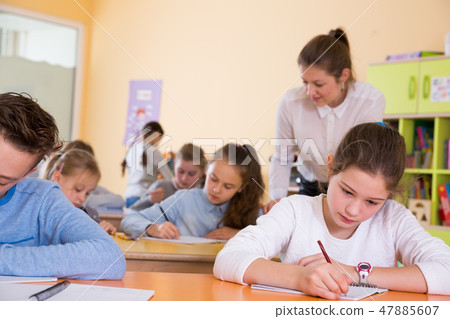 School kids studying in classroom with teacher 47885607