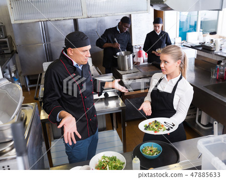 Waitress with dish talking with puzzled chef 47885633