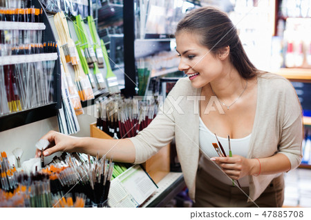 Portrait of cheerful woman choosing brushes for drawing 47885708