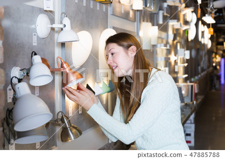 Cheerful female choosing new torchere in store Cheerful female choosing new torchere in store 47885788