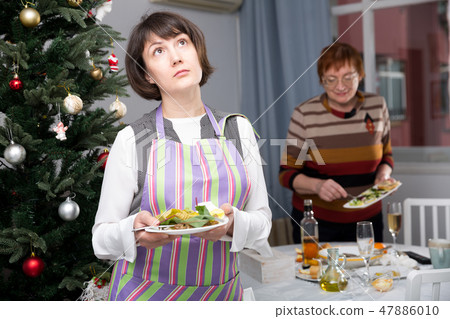 Mature mother with adult daughter laying christmas table Mature mother with adult daughter laying christmas table 47886010