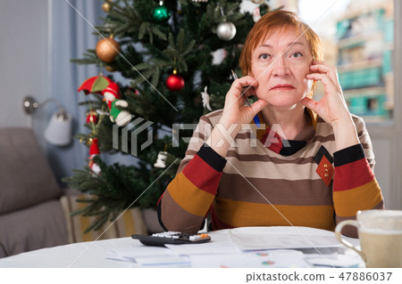 Mature woman calculates utility costs in the new year 47886037