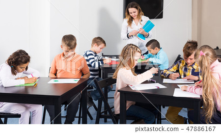 Children in elementary age drawing at classroom 47886167
