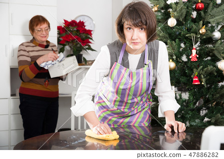 Mature mother with adult daughter tidying up the room before Christmas Mature mother with adult daughter tidying up the room before Christmas 47886282