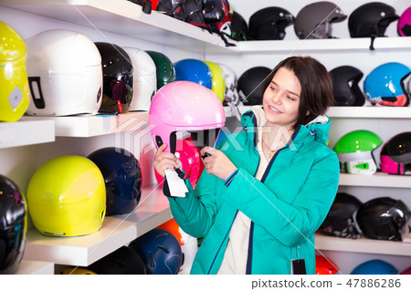 Cheerful girl looking for colorful skiing helmet 47886286